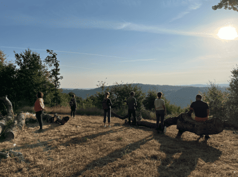 Groupe de personnes dans la nature contemplant une vue vallonnée